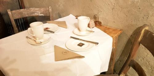 维尔雅尔姆Le Lodge des Flâneurs的一张带两个杯子和盘子的白色桌子