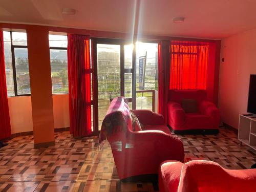 万卡约CASA HOSPEDAJE LAS MONTAÑAS的客厅配有红色家具和窗户。