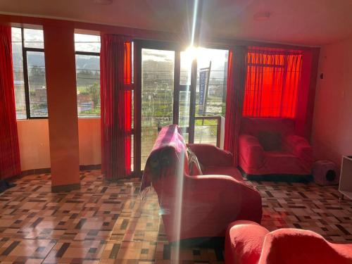 万卡约CASA HOSPEDAJE LAS MONTAÑAS的客厅设有红色家具和大窗户