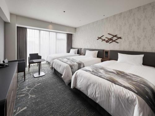 京都Hotel Vischio Kyoto by GRANVIA的酒店客房配有两张床和一张书桌