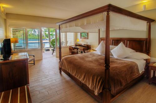 麦克坦种植园湾温泉度假村的一间卧室配有一张天蓬床和一张书桌