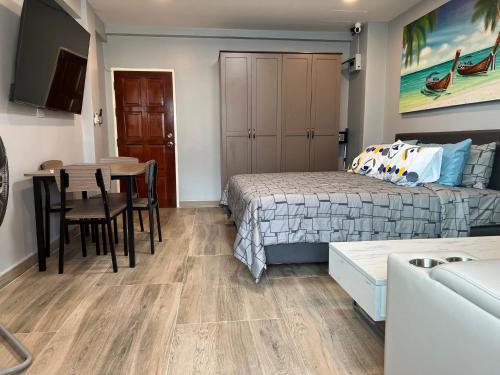 芭东海滩Patong Vacation Rentals - 28 SQM Studio Apartments - Located in the Heart of Patong with Kitchen, Private Bathroom, Seating Area, 65" Smart TV with Free WIFI的一间卧室配有一张床铺和一张桌子,还有一间用餐室