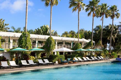 迈阿密海滩金普顿赛康贝酒店的度假酒店的游泳池配有椅子和遮阳伞