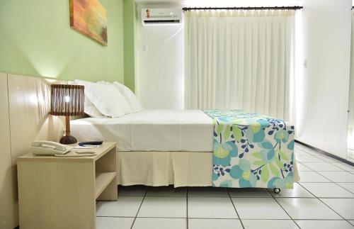 巴雷里尼亚斯Hotel- Gran lençóis flat 408的一间卧室配有一张床和一部电话