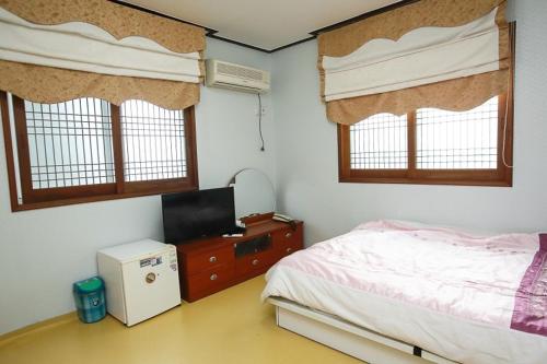 济州市Jun Motel的一间卧室设有一张床、一台电视和窗户。