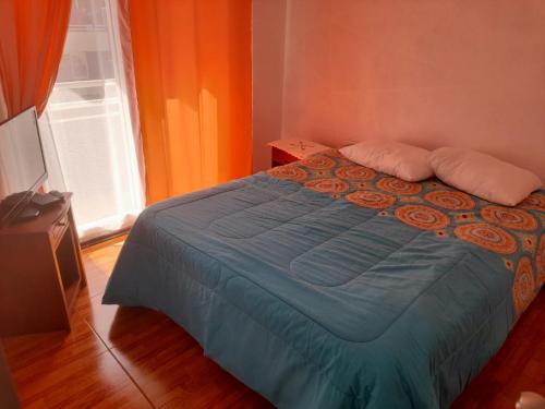拉塞雷纳Departamento verano la serena的一间卧室配有一张蓝色的床和橙色的墙壁