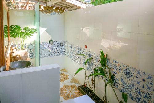 蓝梦岛Lembo Lagoon Bungalows的浴室的墙壁上铺有蓝色和白色的瓷砖。