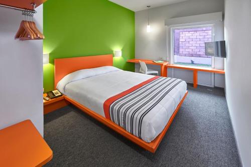 托卢卡City Express Junior by Marriott Toluca Aeropuerto的一间卧室设有一张床和绿色的墙壁