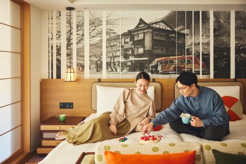 箱根Hotel Indigo Hakone Gora, an IHG Hotel的坐在床上吃食物的男人和女人