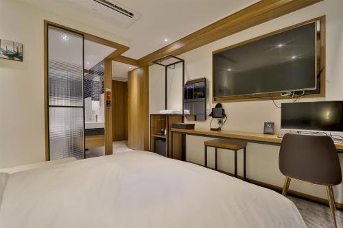 釜山Hotel Brooks Busan Gijang的一间卧室配有一张床和一张书桌及电视
