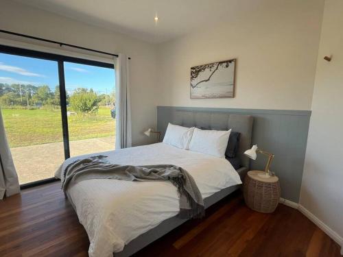 Salt AshThe Ranch - Coastal Farmhouse midway to Newcastle Airport and Beaches的一间卧室设有一张床和一个大窗户