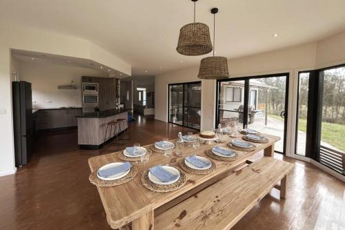 Salt AshThe Ranch - Coastal Farmhouse midway to Newcastle Airport and Beaches的客厅里一张木桌,上面放有盘子和玻璃杯