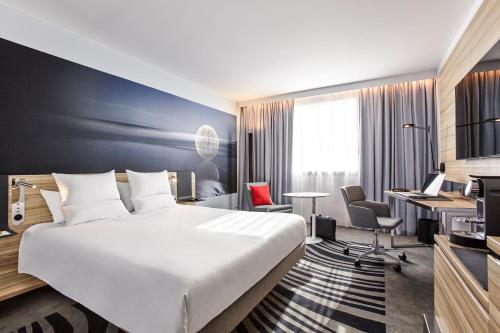 里摩日里摩日湖诺富特酒店的酒店客房设有一张大床和一张书桌。