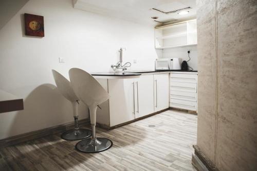 科威特特伦斯福尔尼希德公寓式酒店 - 芬塔斯1号的一间厨房,在房间内配有两把白色椅子