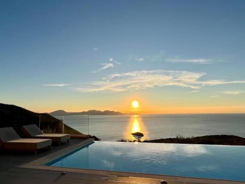 费斯卡尔德宏Entheos Private Villa Fiskardo Kefalonia Greece的日落时分享有海洋美景的游泳池