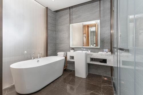 巴中平昌香榭里智选假日酒店的浴室配有大型白色浴缸和水槽