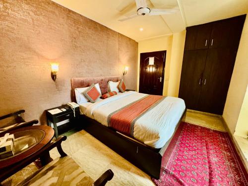 拉合尔Shelton Hotel Lahore的一间卧室配有一张床、一张桌子和一张桌子