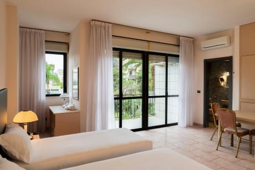 巴里B&B HOTEL Bari Rondò的酒店客房设有两张床、一张桌子和一张桌子。