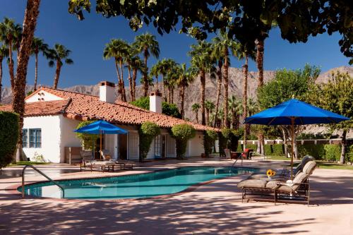 拉昆塔La Quinta Resort & Club, Curio Collection的房屋旁的游泳池配有椅子和遮阳伞