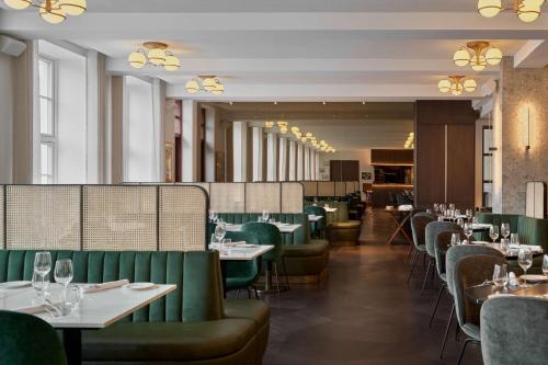 雷克雅未克Iceland Parliament Hotel, Curio Collection By Hilton的用餐室配有桌子和绿色椅子