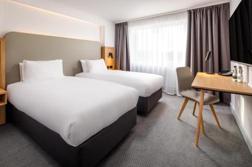 巴塞尔顿假日巴斯尔登酒店的酒店客房配有两张床和一张书桌