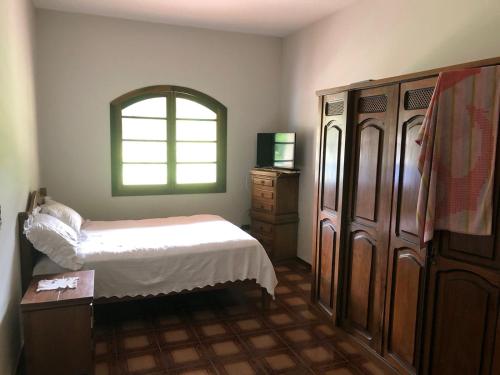 皮尼亚尔齐纽Sitio的一间卧室配有一张床、一个梳妆台和一扇窗户。
