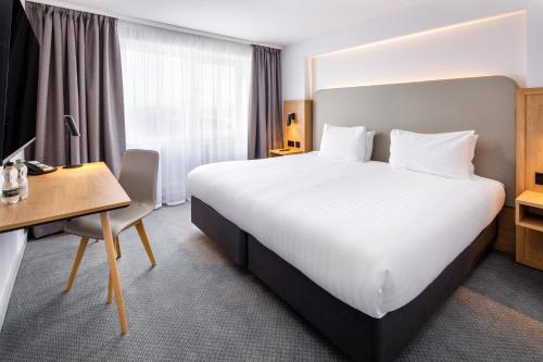 巴塞尔顿假日巴斯尔登酒店的酒店客房设有一张大床和一张书桌。