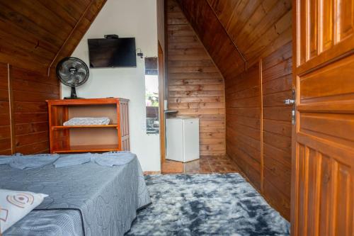 戈亚斯州上帕莱索Chalés Carrara的小房间设有一张床和一个风扇