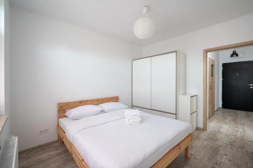 华沙Krzyżówki Comfort Apartment的白色卧室配有一张带白色床单的大床
