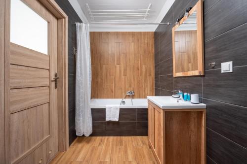 华沙Krzyżówki Comfort Apartment的浴室配有盥洗盆和浴缸。