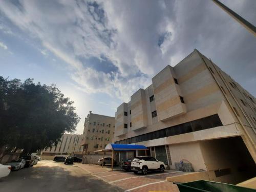 达曼الساعه 60 الفندقيه的停车场内有车辆的建筑物