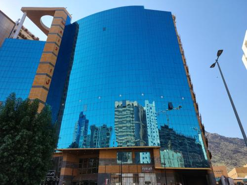 麦加فندق إي دبليو جي العزيزية的一座玻璃建筑,反映了一个城市