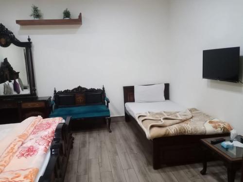 木尔坦Hotel PAK Continental Multan的一间卧室设有两张床,墙上配有电视。
