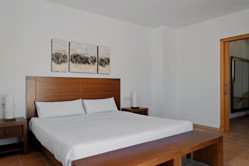 卡拉加尔达纳Prinsotel Villas Cala Galdana的卧室配有白色的床,墙上挂有两幅画作