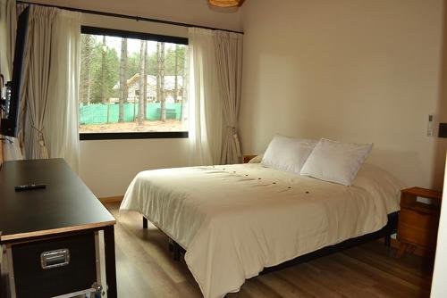 圣马丁德洛斯Chapelco Golf - Cabaña a Estrenar的一间卧室设有一张大床和一个窗户。