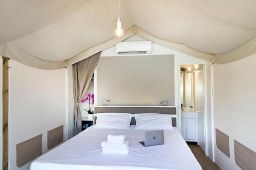 因普鲁内塔Firenze Certosa camping的一间卧室配有一张白色的床,上面有笔记本电脑