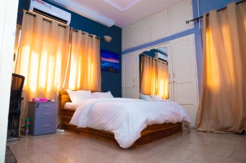 洛美Studio cosy climatisé的一间卧室配有一张大床,拥有蓝色的墙壁和窗帘