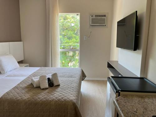 弗洛里亚诺波利斯Caravaggio Praia Hotel的一间卧室配有带毛巾的床和平板电视