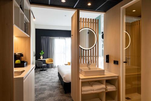 罗森达尔Otium Hotel Roosendaal的酒店客房设有床、水槽和镜子