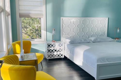 纳瓦拉Holley Point Holiday House的卧室配有白色的床和黄色的椅子