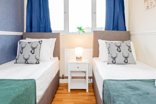 EarleyCosy 3 Bedroom House with Free Parking and Garden的小房间设有两张床,配有蓝色窗帘