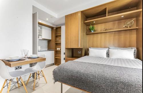直布罗陀West One Studio Apartments的一间带一张床和一张书桌的卧室和一间厨房