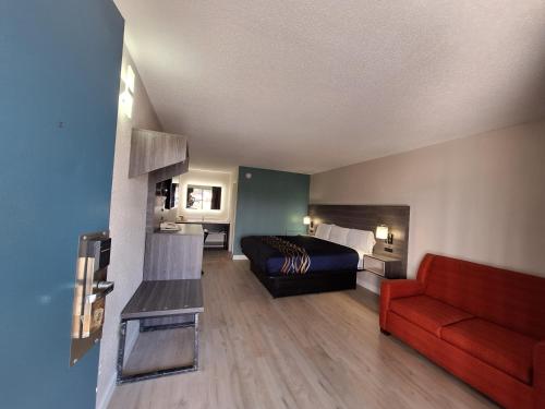 Roxboro经济汽车旅馆 - 罗克斯伯勒的酒店客房,配有一张床和一张红色的沙发