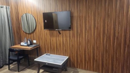 古瓦哈提N.K. Residency的木墙上配有电视的房间