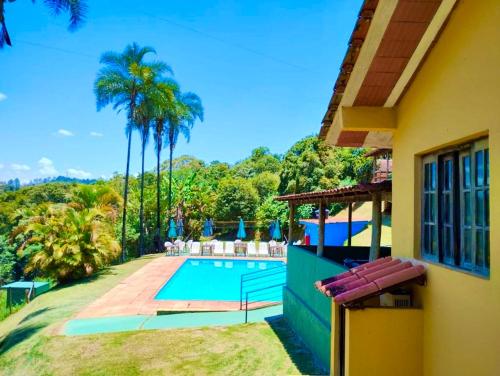 马卡科斯Pousada Recanto do Chalé Ltda的一座带游泳池和棕榈树的房子