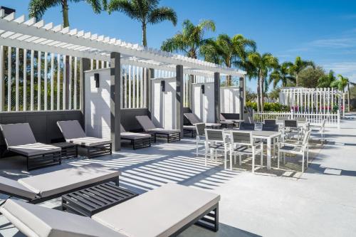 萨拉索塔DoubleTree by Hilton Sarasota Bradenton Airport的一个带桌椅的庭院,棕榈树