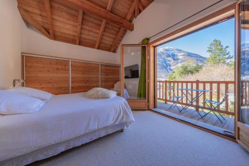 拉萨尔莱阿尔佩Chalet Snowbird 5 étoiles, Serre-Chevalier的一间卧室设有一张床和一个美景阳台
