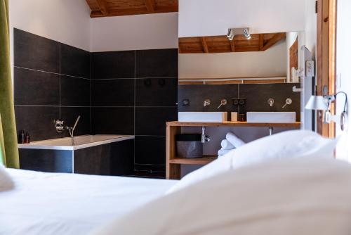 拉萨尔莱阿尔佩Chalet Snowbird 5 étoiles, Serre-Chevalier的一间卧室配有一张床、一个浴缸和一个水槽