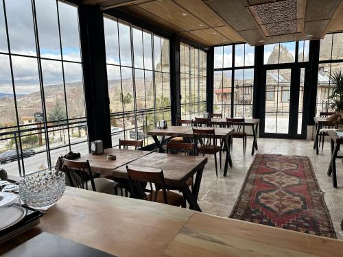 格雷梅Turan Cappadocia Cave的餐厅设有桌椅和大窗户。