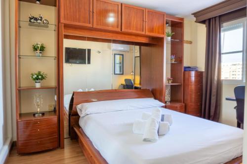 马拉加Apartment Aconte Malaga的一间卧室配有一张带白色床单和木制橱柜的床。